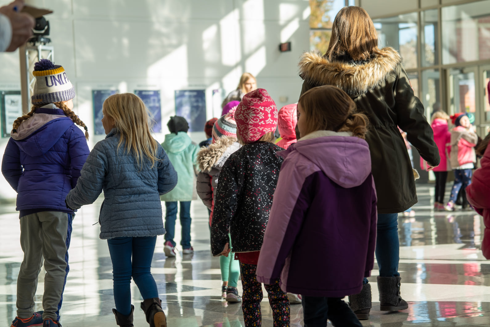 Children filing through the lobby of the Gallagher Bluedorn in winter clothes. 