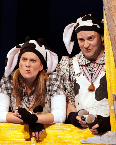 Two actors in cow costumes look puzzled