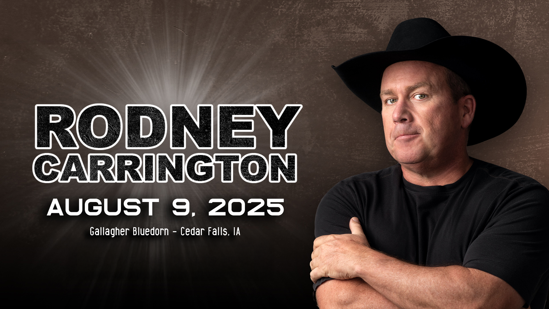A man wearing a black cowboy hat and black shirt looking at the camera 
