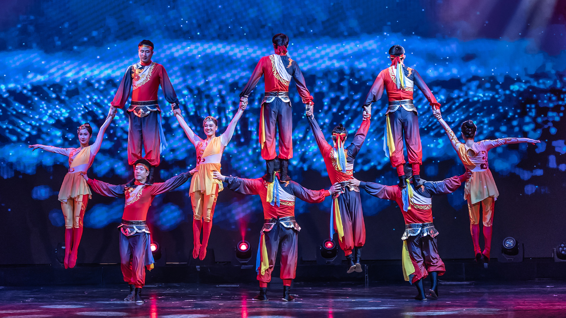 A group in a circus standing on top of each other creating a pyramid 