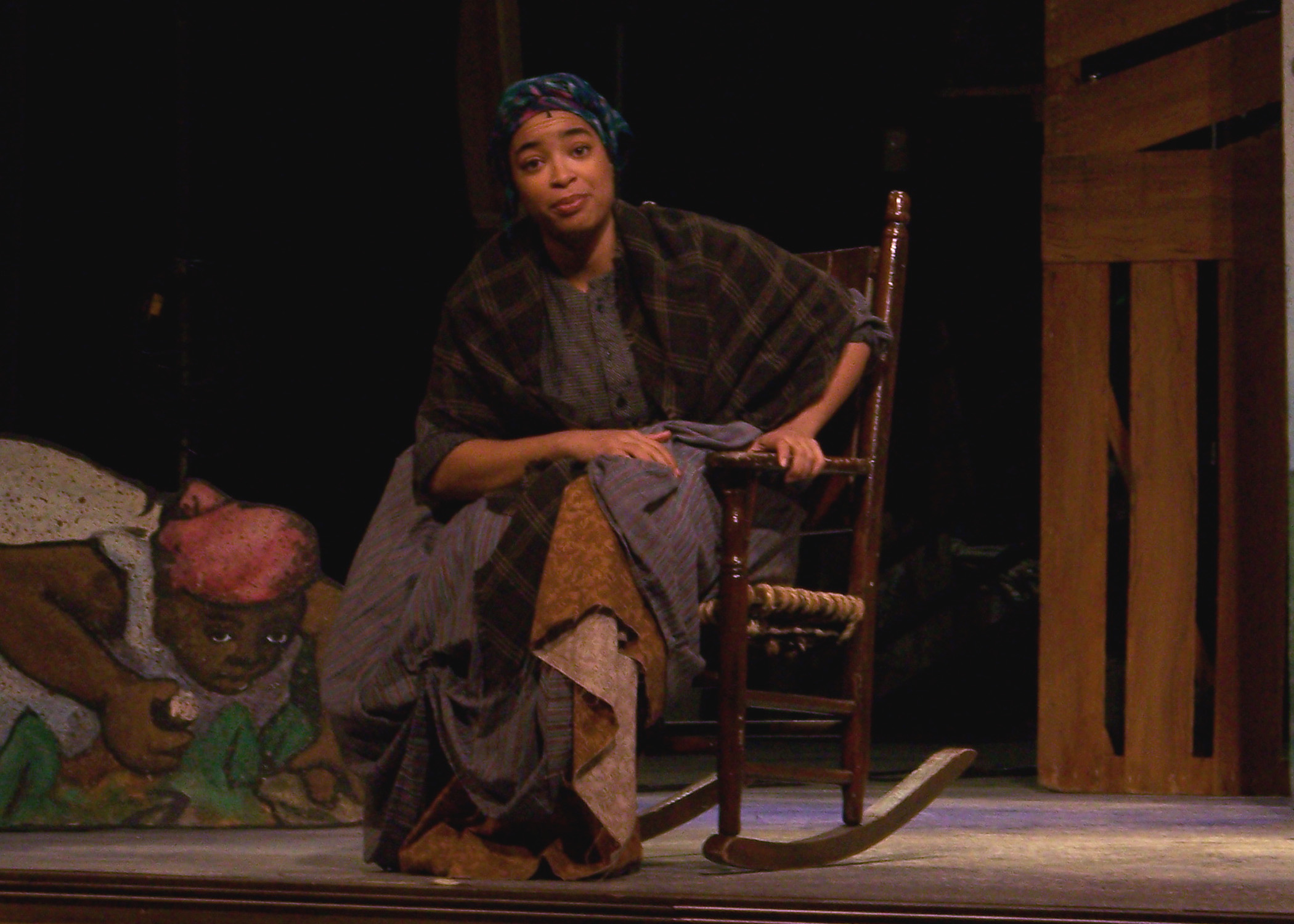 Actor sitting in a rocking chair on stage.