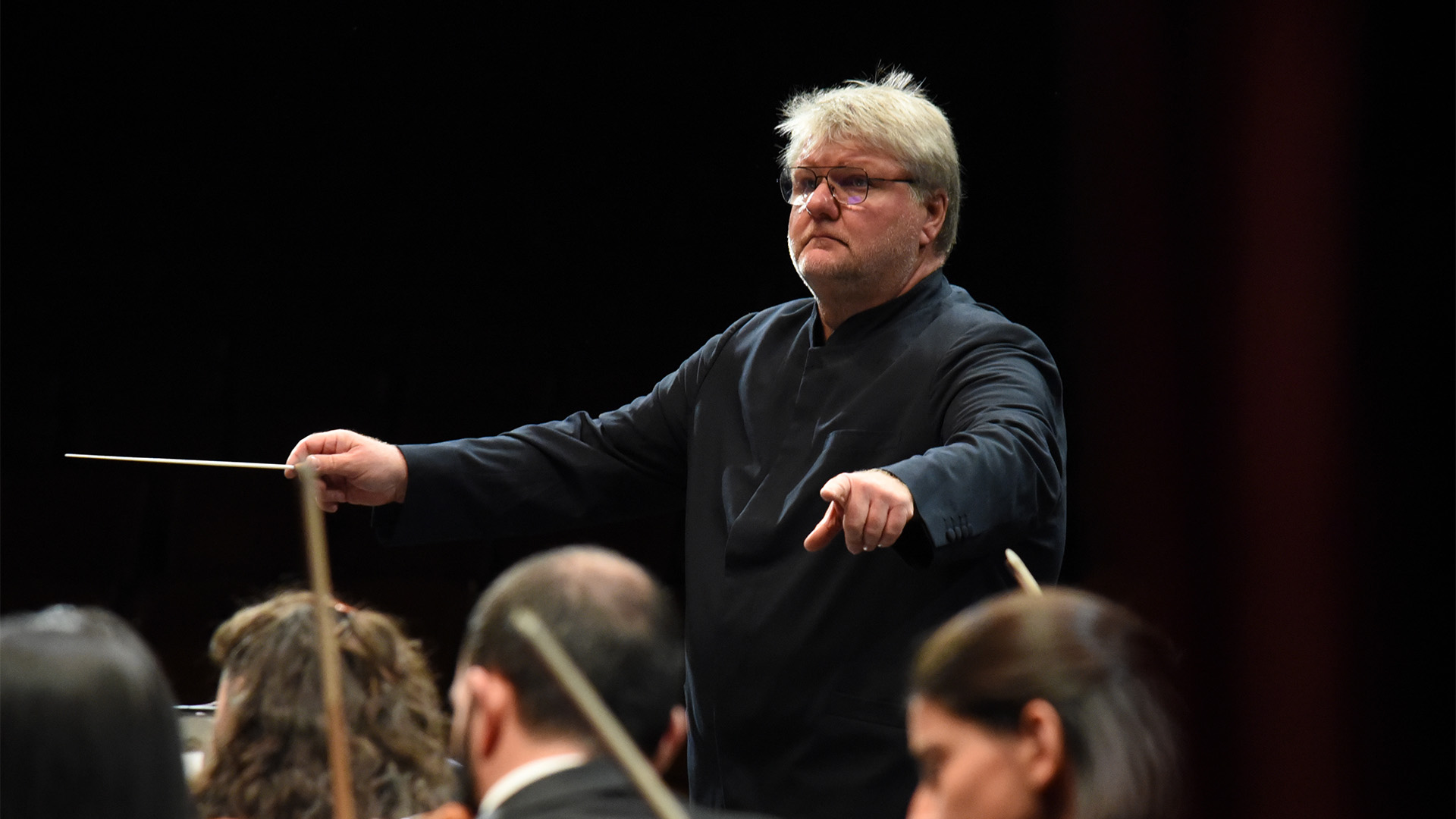man in black conducting orchestra