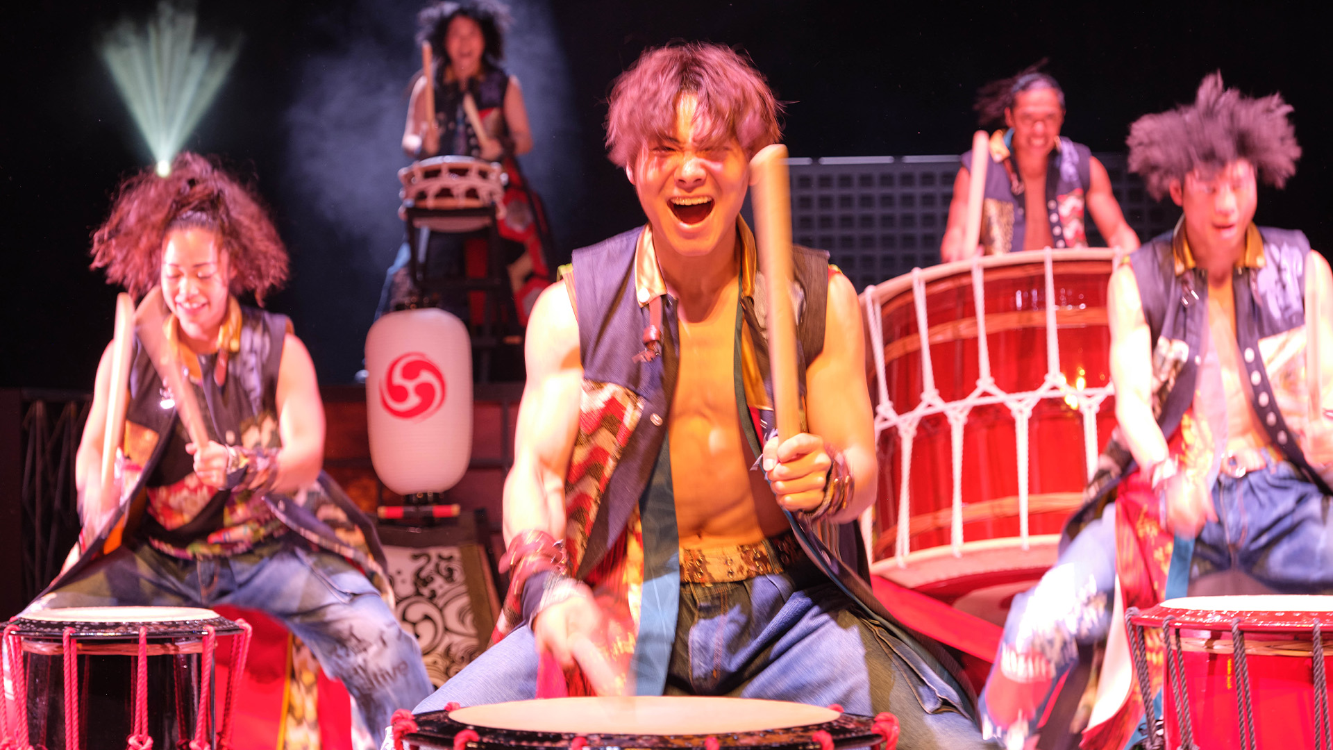 An excited group banding on big drums 