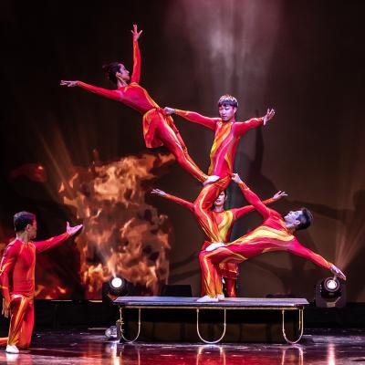 A circus group dressed in red doing tricks standing on each other