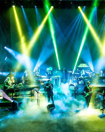 A band playing on stage with lots of smoke and lights shining in the air
