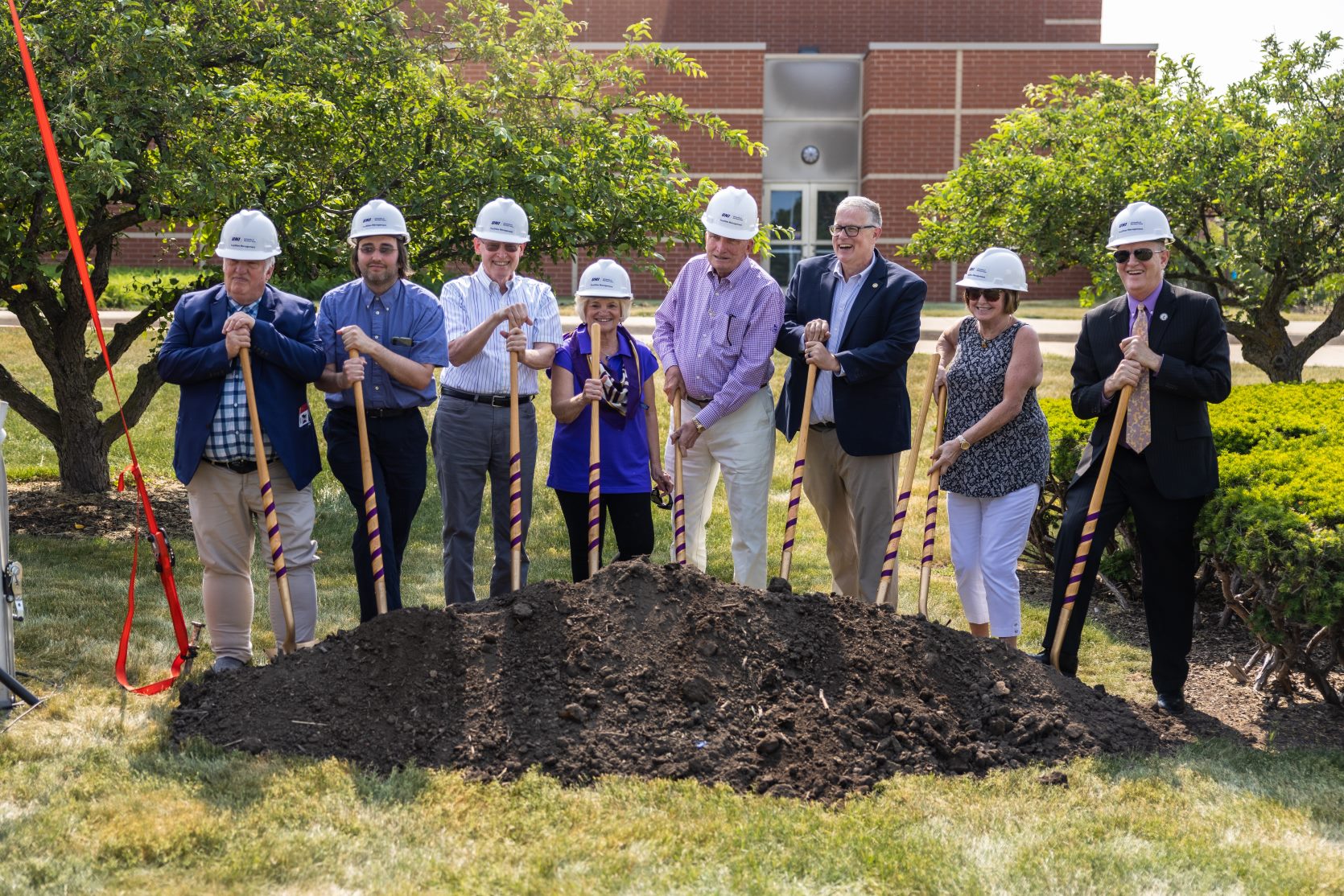Group standing near pile with shovels
