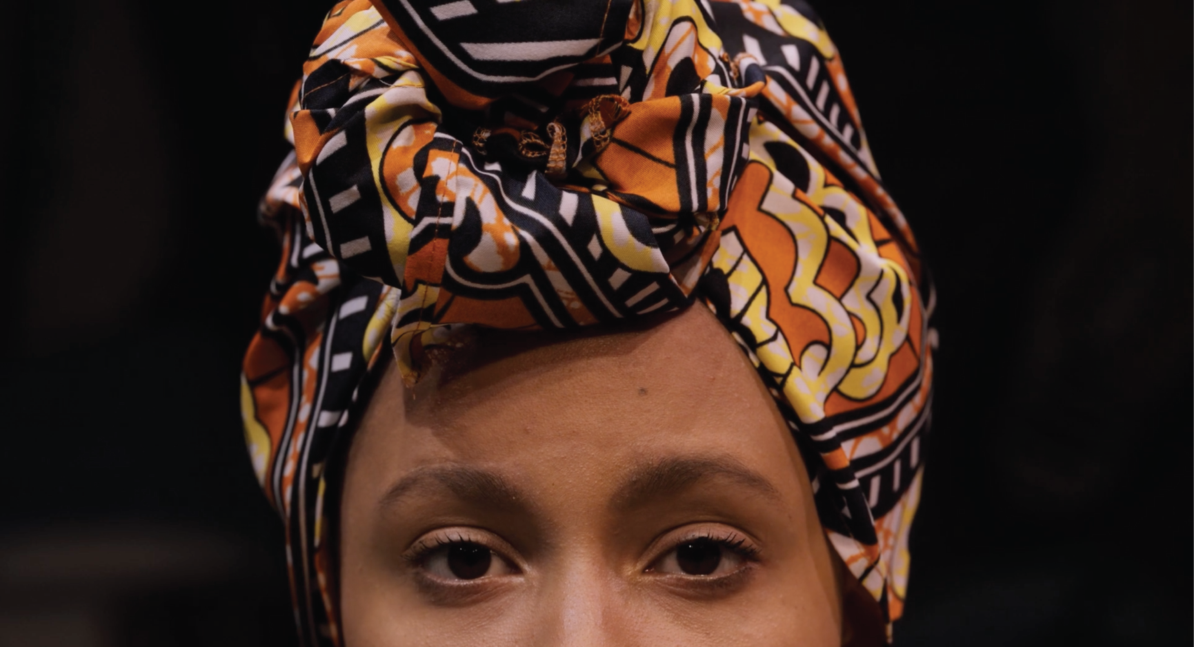 Someone wearing a headwrap and their eyes staring directly ahead. You can only see from the nose up.