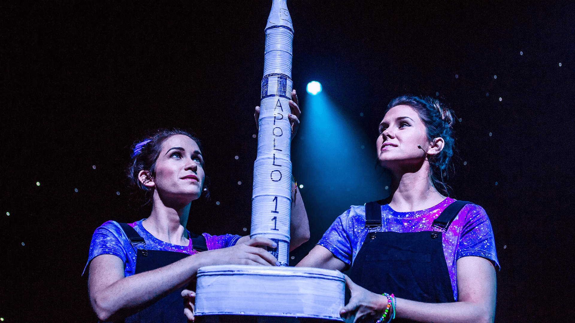 Two people hold up a model rocket of a spacecraft 