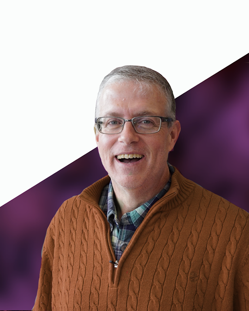 Steve Carignan wearing a rust colored sweater with a purple and white background.