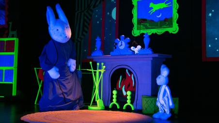 A puppet bunny and a smaller puppet bunny in the living room of a house 